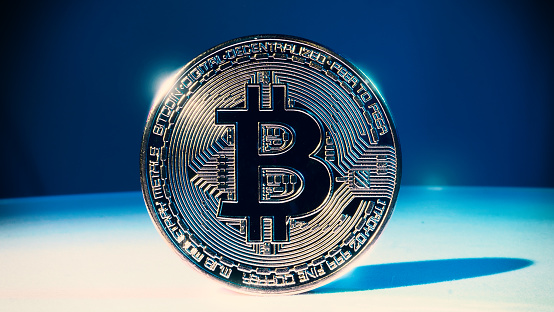 Cryptocurrency Bitcoin on white floor and colorful background. Cryptocurrency. Crypto assets. Bitcoin coin with studio light.