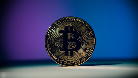 Cryptocurrency Bitcoin on white floor and colorful background. Cryptocurrency. Crypto assets. Bitcoin coin with studio light.
