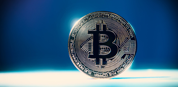 Cryptocurrency Bitcoin on white floor and colorful background. Cryptocurrency. Crypto assets. Bitcoin coin with studio light.