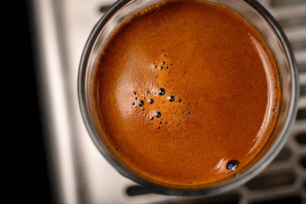 close-up on brown foam with bubbles of coffee drink in round glass