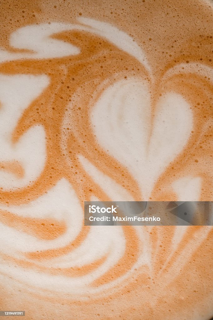 close-up of beautiful white milk patterns on brown foam of coffee drink. close-up top view of beautiful white milk art patterns on brown foam of coffee drink. Froth Art Stock Photo