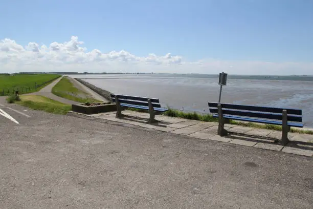 two benches along the road at the seawall with a beautiful view at scheldt river with mudflats in zeeland in springtime