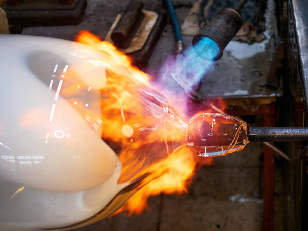 istock Master glassmaker heats a fire torch glass ball on a glass pipe. 1319497210