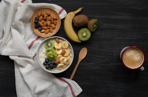 bowl with banana, blueberry, granola, oat, kiwi and coffee