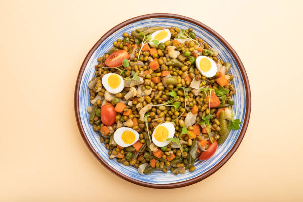 istock Mung bean porridge with quail eggs, tomatoes and microgreen sprouts on a pastel orange background. Top view, close up. 1319508949