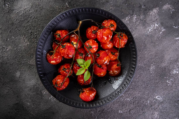 istock Black plate with confit tomatoes on dark background 1319508994