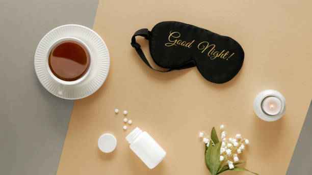 qualité du sommeil. masque de sommeil, somnifères, bougie parfumée et tasse de thé calmant. deux tons argenté papier beige or plat jeter. texte bonne nuit sur le masque. lys des fleurs de vallée - the splits photos et images de collection