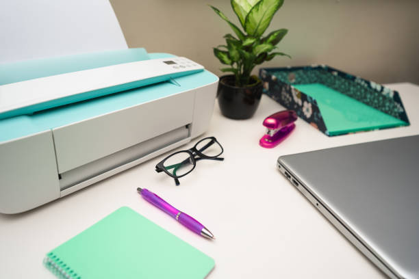 White office desk with laptop, printer, glasses and supplies. Selective focus.