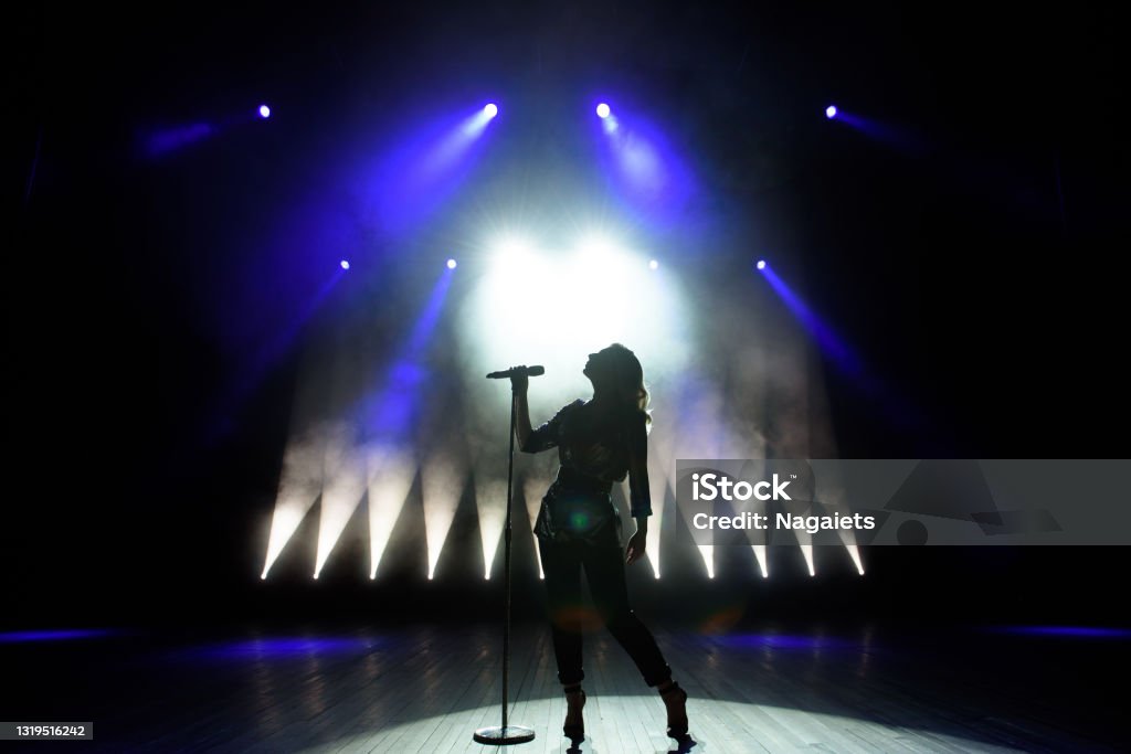 Silhouette of singer on stage. Dark background, smoke, spotlights. Silhouette of singer on stage. Dark background, smoke, spotlights Women Stock Photo