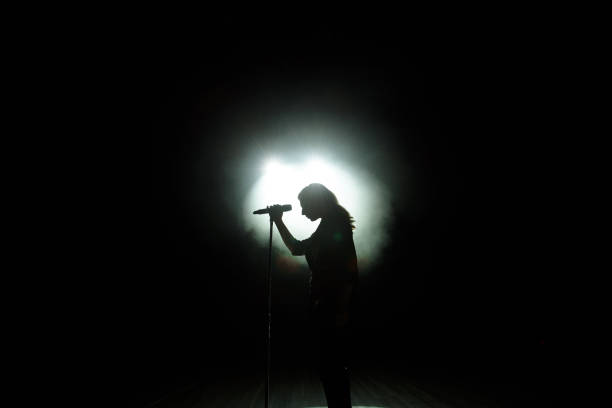 silhouette nera della cantante femminile con faretti bianchi sullo sfondo - microphone stage music popular music concert foto e immagini stock