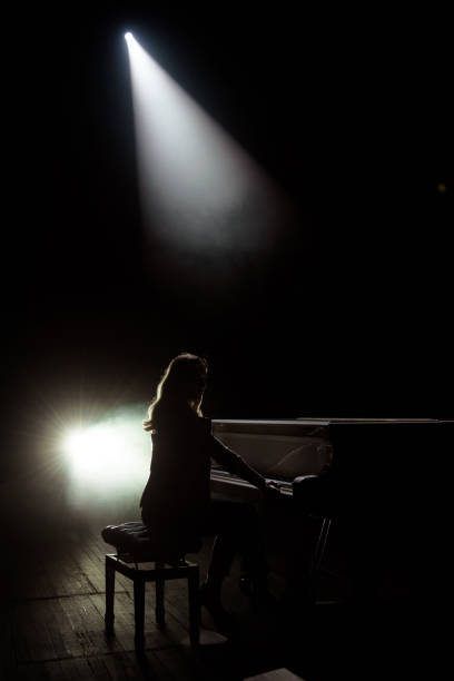 istock Female keyboards player on stage during concert, backlight 1319516273