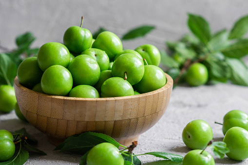 Fresh ripe organic green plums or greengage in bowl, heap of summer fruits concept
