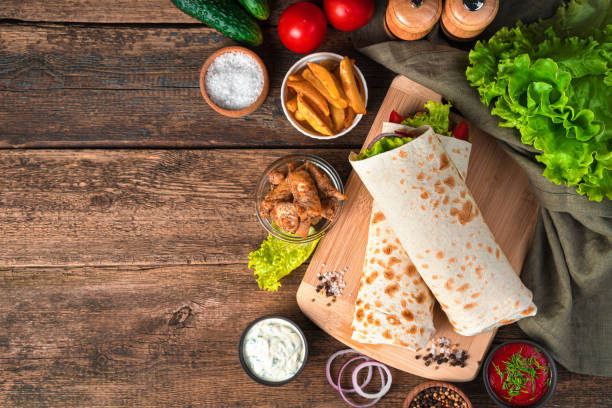 istock Burrito with chicken and vegetables on a brown background with fresh ingredients 1319518475