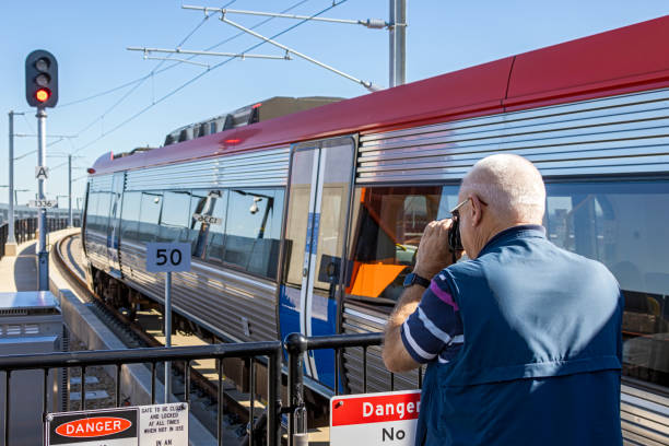 senior männlich trainspotter auf demstation plattform fotografieren von elektro-zug - eisenbahnfan stock-fotos und bilder