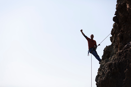 Young man enjoys success on top of a cliff