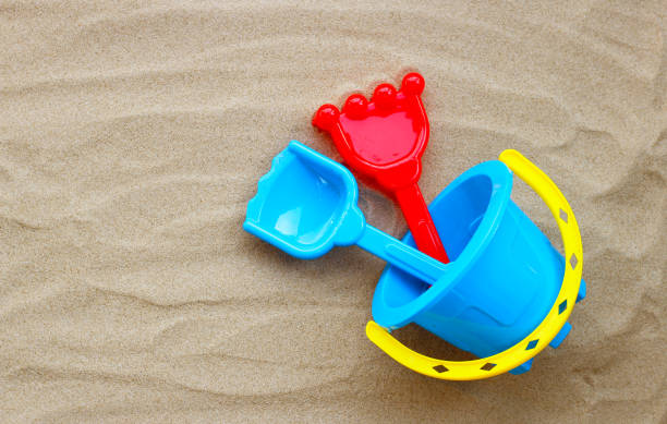 istock Plastic toys, shovel and bucket on sand on white background. Summer background concept 1319528554