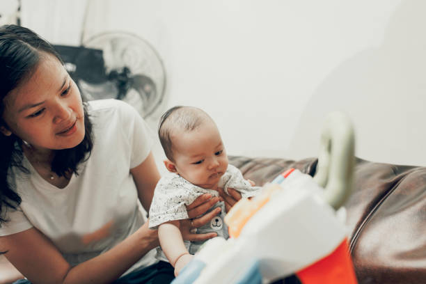 istock Mother is playing with her little baby on the sofa 1319535667