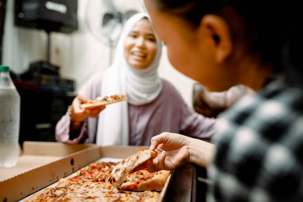 istock young muslim women having breakfast with pizza at ramadan 1319535720