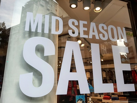 Shop window and city reflections in Buenos Aires, Argentina. Mid season sale advertisement. May 22, 2021.