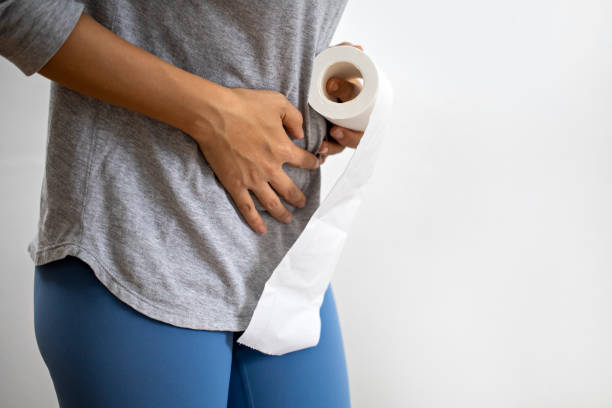 Midsection Of Woman Suffering From Stomachache And Tissue Or Toilet Paper Roll stock photo