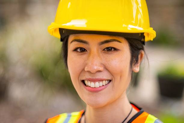 istock Smiling asian female construction worker wearing a work helmet looking at the camera 1319541780