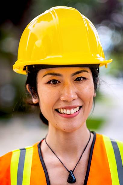 istock Smiling asian female construction worker wearing a work helmet looking at the camera 1319541820