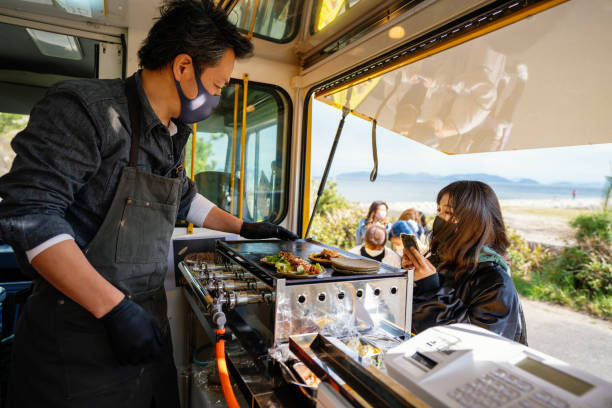 Woman taking a picture with her smart phone while waiting in line at a food truck