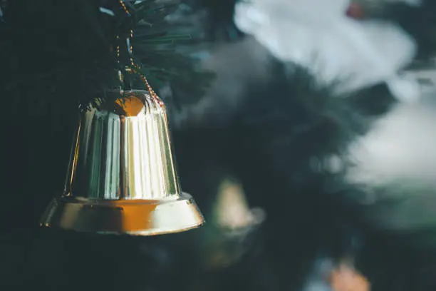 Photo of Close up of Christmas gold colour bell hanging on Christmas tree, ornaments