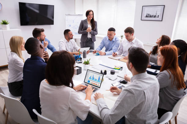 Smiling Young Businesswoman Giving Presentation In The Meeting Group Of Smiling Young Multi Ethnic Businesspeople Looking At Businesswoman Giving Presentation In The Meeting shareholder stock pictures, royalty-free photos & images