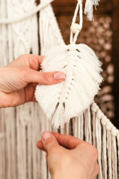 istock Close-up of a woman's hands holding a macrame-style decor made of white cotton threads.Handmade concept.Home decor. 1319548099