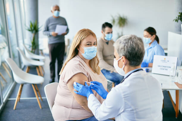 istock Woman with face mask getting vaccinated against coronavirus at vaccination center. 1319550717