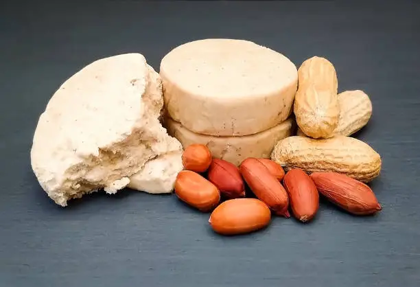 Traditional sweet Mazapán next to peanuts on gray wooden background.