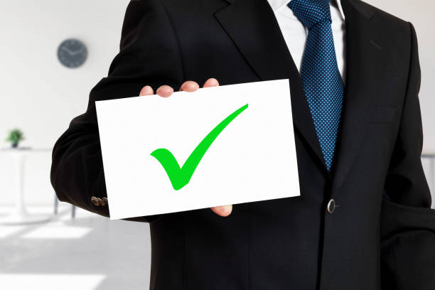 istock Businessman holds a card with the tick or check mark icon. Successful task completion or business evaluation 1319554312