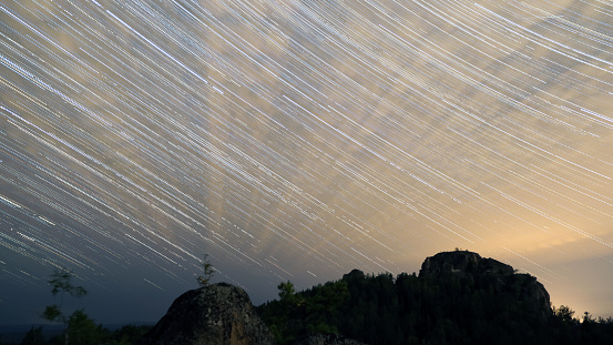 Tracks of stars and clouds over the Siberian taiga and mountains in the Krasnoyasrky Nature Park Stolby.