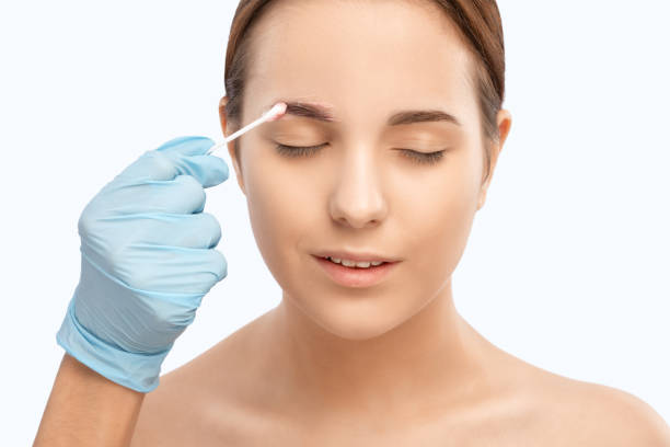 istock Make-up artist makes markings with white pencil for eyebrow and paints eyebrows. Professional makeup and facial care. 1319557712