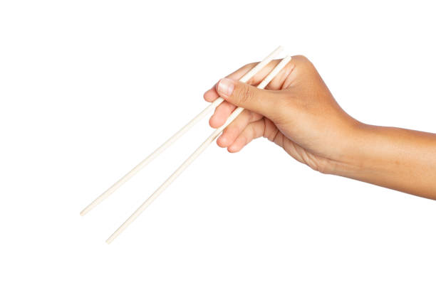 istock hand holding wooden chopsticks isolated on white background. 1319564200