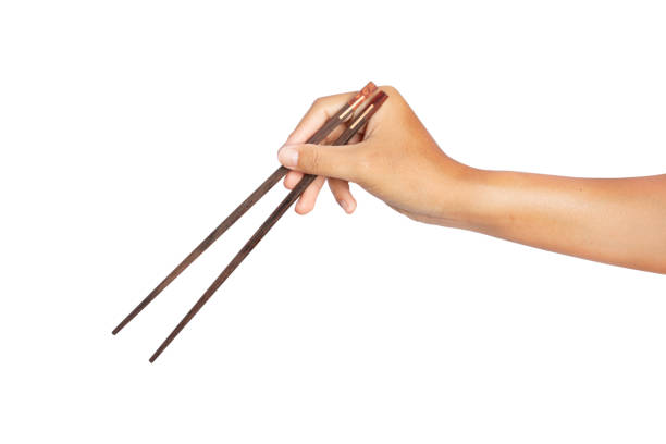 istock hand holding wooden chopsticks isolated on white background. 1319564207
