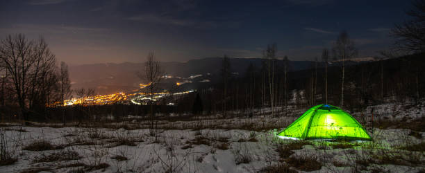 tenda gialla di notte in inverno in montagna sullo sfondo del villaggio - group21 foto e immagini stock