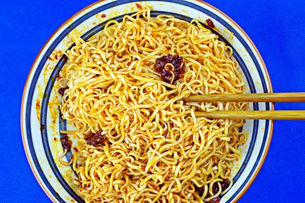 istock Noodle, chopsticks and chili paste on plate - blue background. 1319566589