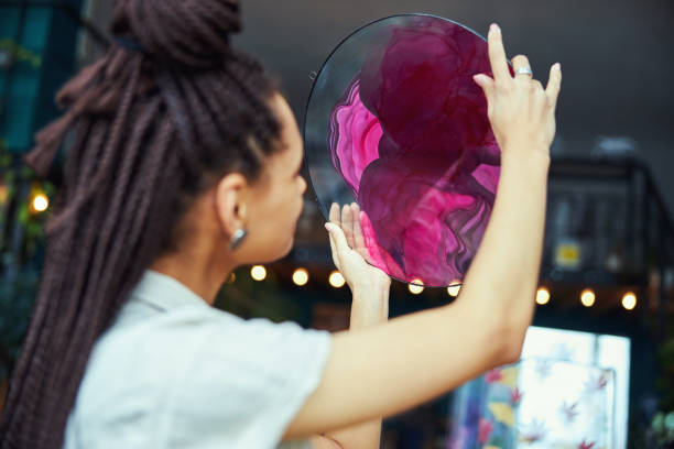 istock Painter looking at a circular fluid art painting in her hands 1319577172