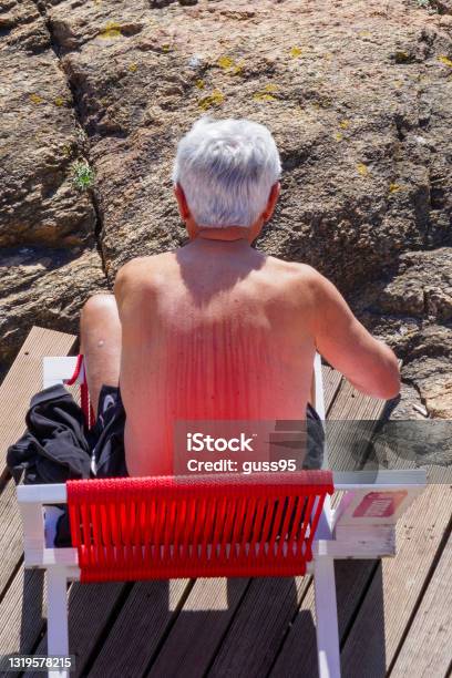 Foto de Costas Marcadas Com Listras Vermelhas Por Um Leito De Sol Velho Queimado Seared Tomando Sol Sobre As Rochas e mais fotos de stock de Adulto