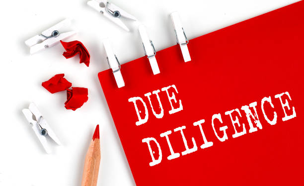 DUE DILLIGENCE text on red paper with office tools on white background stock photo