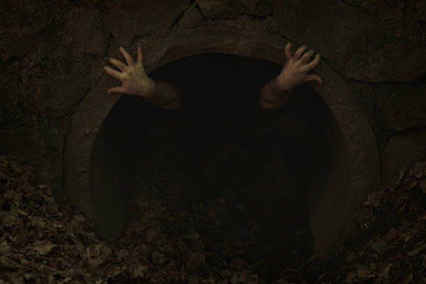 pequena abertura de túnel escuro com duas mãos com dedos torcidos cutucando para fora e segurando até a borda, alguém tentando sair - dark edge - fotografias e filmes do acervo