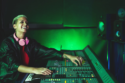 Young woman working in music recording studio - Female audio engineer mixing a sound in production house