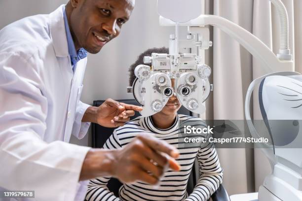 African Young Woman Girl Doing Eye Test Checking Examination With Male Man Optometrist Using Phoropter In Clinic Or Optical Shop Eyecare Concept Stock Photo - Download Image Now