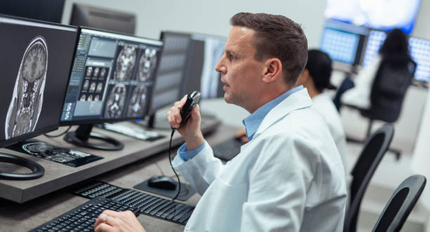 istock Male Radiologist Speaking Into A Dictation Recorder While Looking at MRI Scan 1319587001