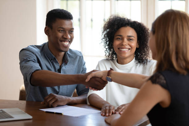 istock Happy young african american clients shaking hands with financial advisor. 1319587076