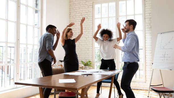 istock Overjoyed millennial diverse mixed race business people dancing in office. 1319587112