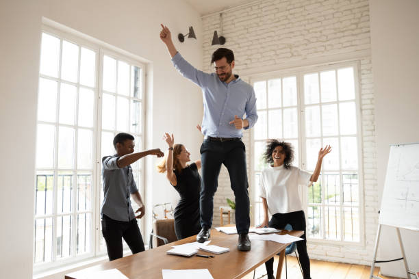 istock Overjoyed emotional young mixed race employees having fun in office. 1319587122