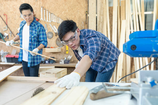 istock Craftsmans working together at carpentry shop. Carpenter working with circular saw at carpentry workshop. 1319587521